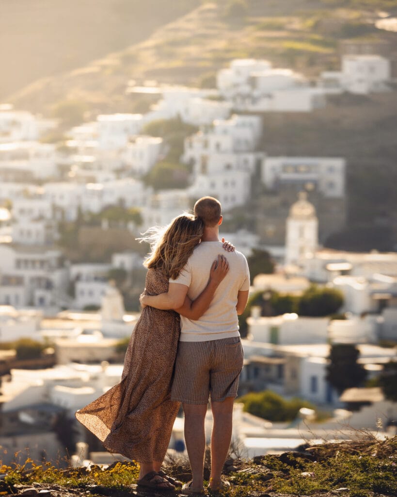 Michelle and Julius embracing above a whitewashed village on Tinos